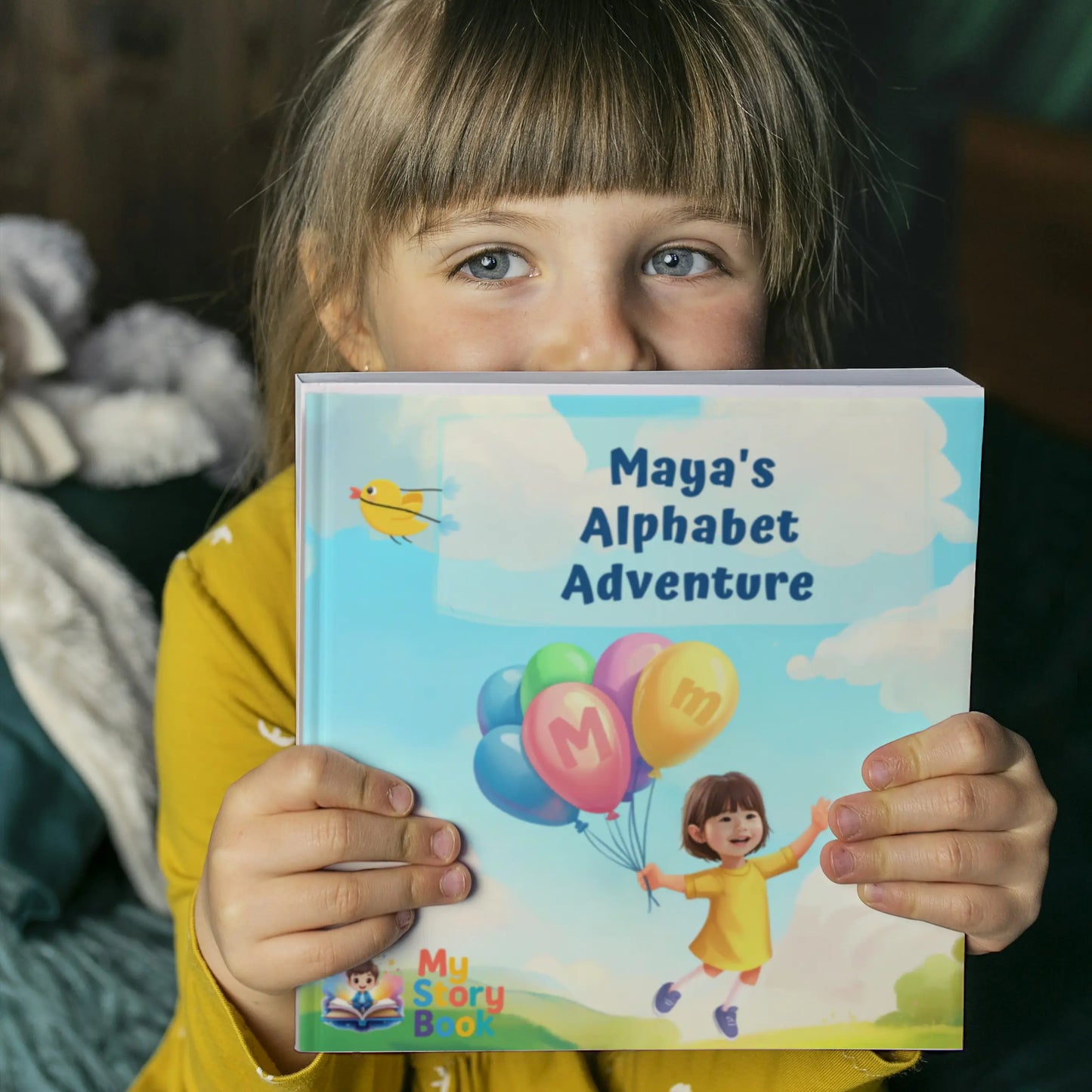A cheerful young child holding the personalized alphabet storybook "Maya's Alphabet Adventure," showcasing the product.